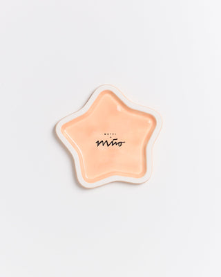 Sternförmiger, orangefarbener Teller mit dem Aufdruck "Motel a Miio" in einem minimalistischen Design auf weißem Hintergrund.