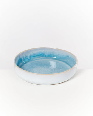 Eine flache Schüssel mit blauer Glasur auf einem weißen Hintergrund.