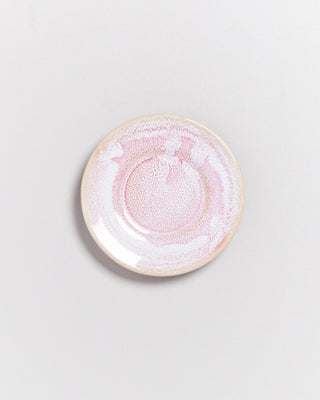 Runder Teller mit rosa und weißen Mustern auf einer neutralen, hellen Oberfläche.