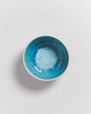 Blaue Keramikschale mit glasiertem Muster auf einer weißen, glatten Oberfläche fotografiert.