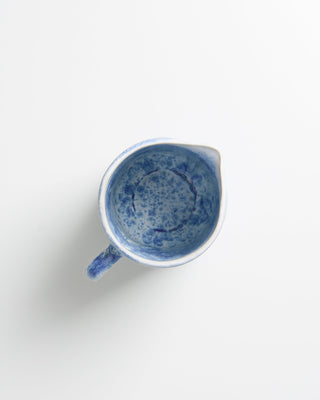 Keramikschale mit blauem Muster, von oben betrachtet, auf weißem Hintergrund.