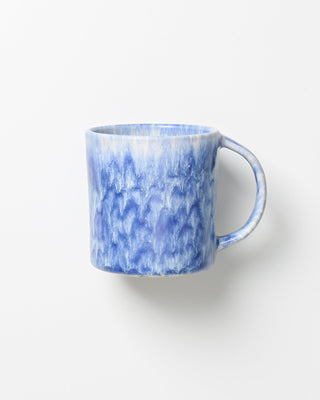 Blaue Keramiktasse mit marmoriertem Muster auf weißem Hintergrund.