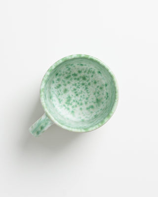 Grüne und weiße marmorierte Tasse von oben auf weißem Hintergrund.