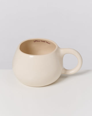 Beige Tasse mit rundem Griff, innen am Rand steht "SPILL THE TEA!".