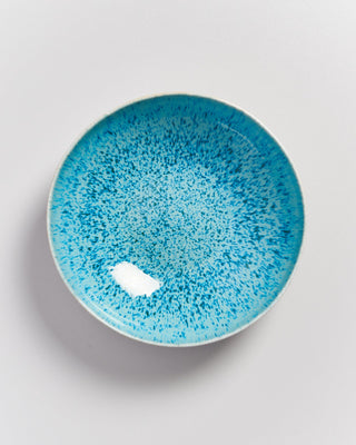 Blaue Keramikschale mit gesprenkeltem Muster auf grauem Hintergrund.