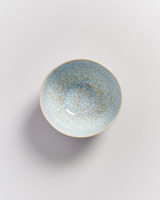 Keramikschale mit blauen und beige gesprenkelten Mustern auf heller Oberfläche.
