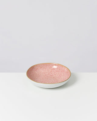 Rosa Schale mit Sprenkeln auf weißem Untergrund vor neutralem Hintergrund.
