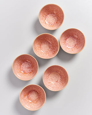 Sechs rosa gesprenkelte Schalen sind auf einem grauen Hintergrund symmetrisch angeordnet.