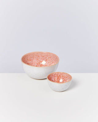Zwei Schalen mit rosa gesprenkelter Innenseite und weißer Außenseite stehen auf einem weißen Tisch.