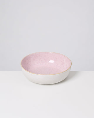 Weiße Schale mit rosa Innenfläche steht auf einem weißen Tisch vor grauem Hintergrund.