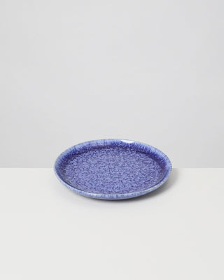 Blauer, gesprenkelter Keramikteller auf einem weißen Hintergrund.