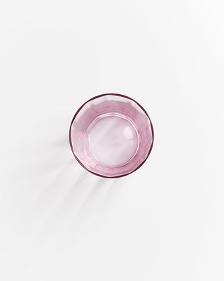 Rosafarbenes, leeres Glas von oben auf weißem Hintergrund fotografiert.