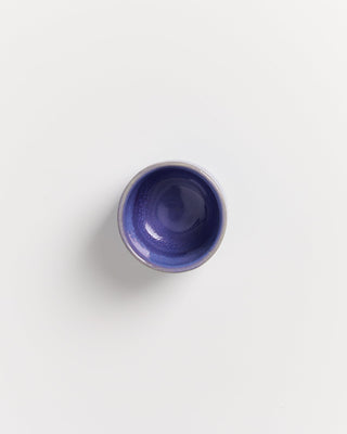 Kleine, blaue Keramikschale auf weißem Hintergrund, von oben fotografiert.