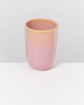 Rosa Vase aus Keramik steht auf einer weißen Oberfläche vor einem grauen Hintergrund.