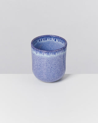 Blauer Keramikbecher mit gesprenkelter Oberfläche auf hellem Hintergrund.