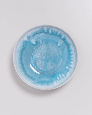 Runder Teller mit blauer, marmorierter Glasur auf einem hellen Untergrund.