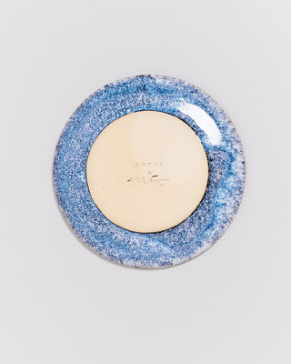 Rückseite eines Keramiktellers mit blauer und beiger Glasur auf weißem Hintergrund.