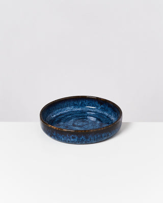 Runde, blaue Keramikschale mit dunklen Rändern auf weißem Hintergrund.