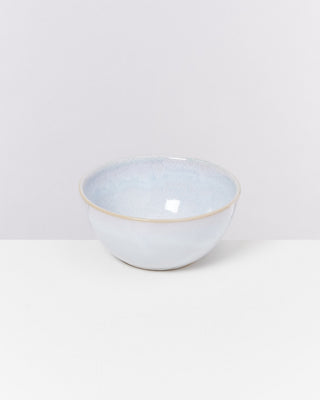 Eine weiße Keramikschale mit einem dezenten blauen Schimmer steht auf einem weißen Tisch vor einem weißen Hintergrund.