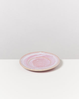 Rosa Keramikteller mit gesprenkeltem Muster auf weißem Untergrund.