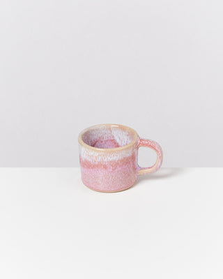 Rosa Tasse mit marmoriertem Design auf einer weißen Oberfläche.