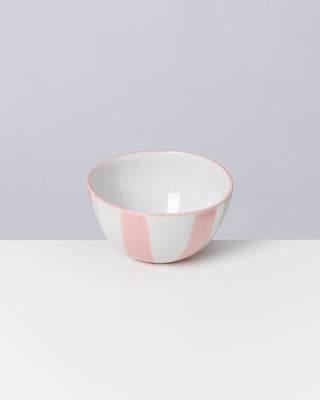 Keramikschüssel mit rosa-weißen Streifen auf einem weißen Tisch vor grauem Hintergrund.
