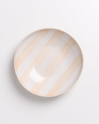 Keramikschüssel mit beige-weißen Streifen auf weißem Hintergrund.