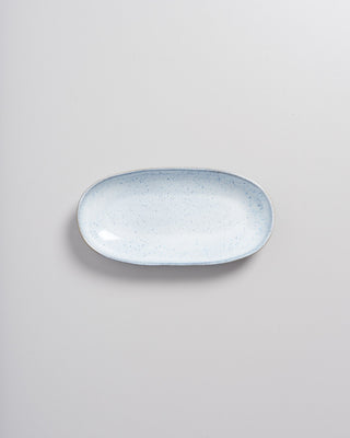 Ovale, hellblaue Keramikschale mit dunklen Sprenkeln auf hellem Hintergrund.