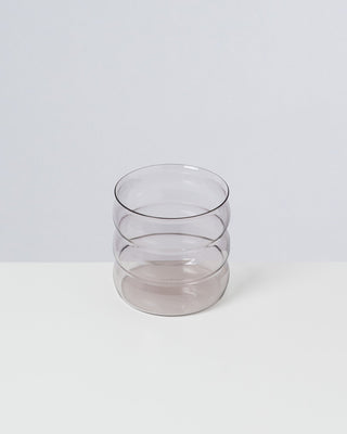 Graues, gestapeltes Glas mit wellenartigem Design auf weißem Hintergrund.