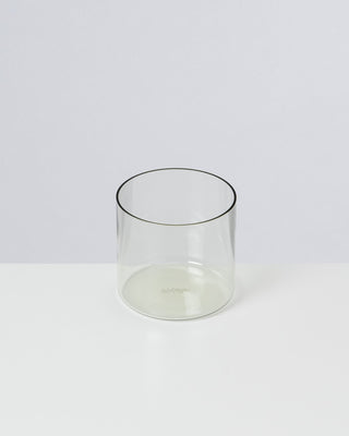 Ein transparentes, zylindrisches Glas steht auf einer weißen Oberfläche.
