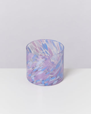 Ein Glasbecher mit lila und blauen Marmorierungsmustern auf einem weißen Hintergrund.