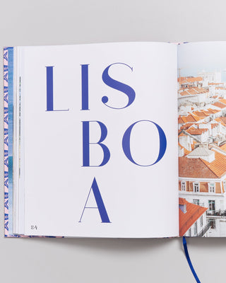 Aufgeschlagenes Buch mit dem Wort "LISBOA" auf der linken Seite und einem Bild von roten Dächern auf der rechten Seite.