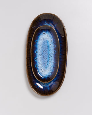 Ovaler Keramikteller mit blauem und braunem Muster auf grauem Hintergrund.