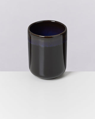 Schwarze, glänzende Keramiktasse mit einem dunkelblauen Rand auf einem weißen Hintergrund.