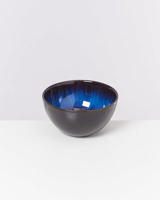 Schwarze Schüssel mit glänzendem blauen Innenfutter, auf weißem Hintergrund.
