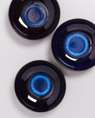 Drei dunkelblaue Keramikteller mit leuchtend blauen, konzentrischen Kreisen in der Mitte auf weißem Hintergrund.
