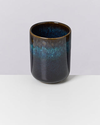 Keramikbecher mit blau-grüner Glasur und braunem Rand auf weißem Hintergrund.