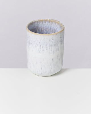 Becher aus Keramik mit blaugrauer Textur auf weißer Oberfläche.