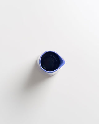 Kleine blaue Kanne mit Ausguss steht auf weißem Hintergrund.