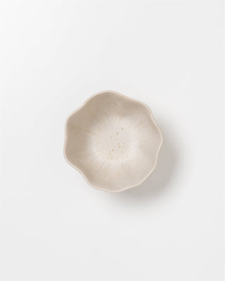 Beige, blütenförmige Schale auf weißem Hintergrund.