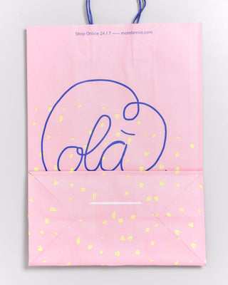 Rosa Papiertüte mit blauen Henkeln, dekoriert mit gelben Punkten und dem Wort "Olá" in großer blauer Schrift.